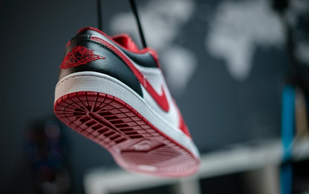 Detailed view of a red and white sneaker hanging in focus, featuring a unique sole design.