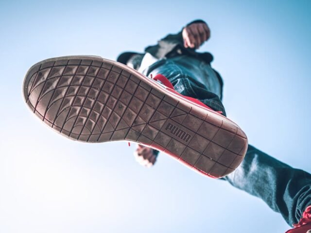 Low angle view of person wearing sneakers with focus on the sole against blue sky.