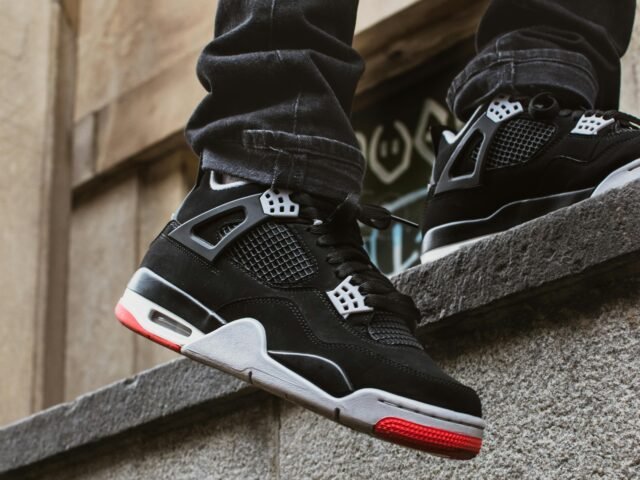 Stylish black sneakers on urban stone wall, perfect for streetwear fashion lovers.